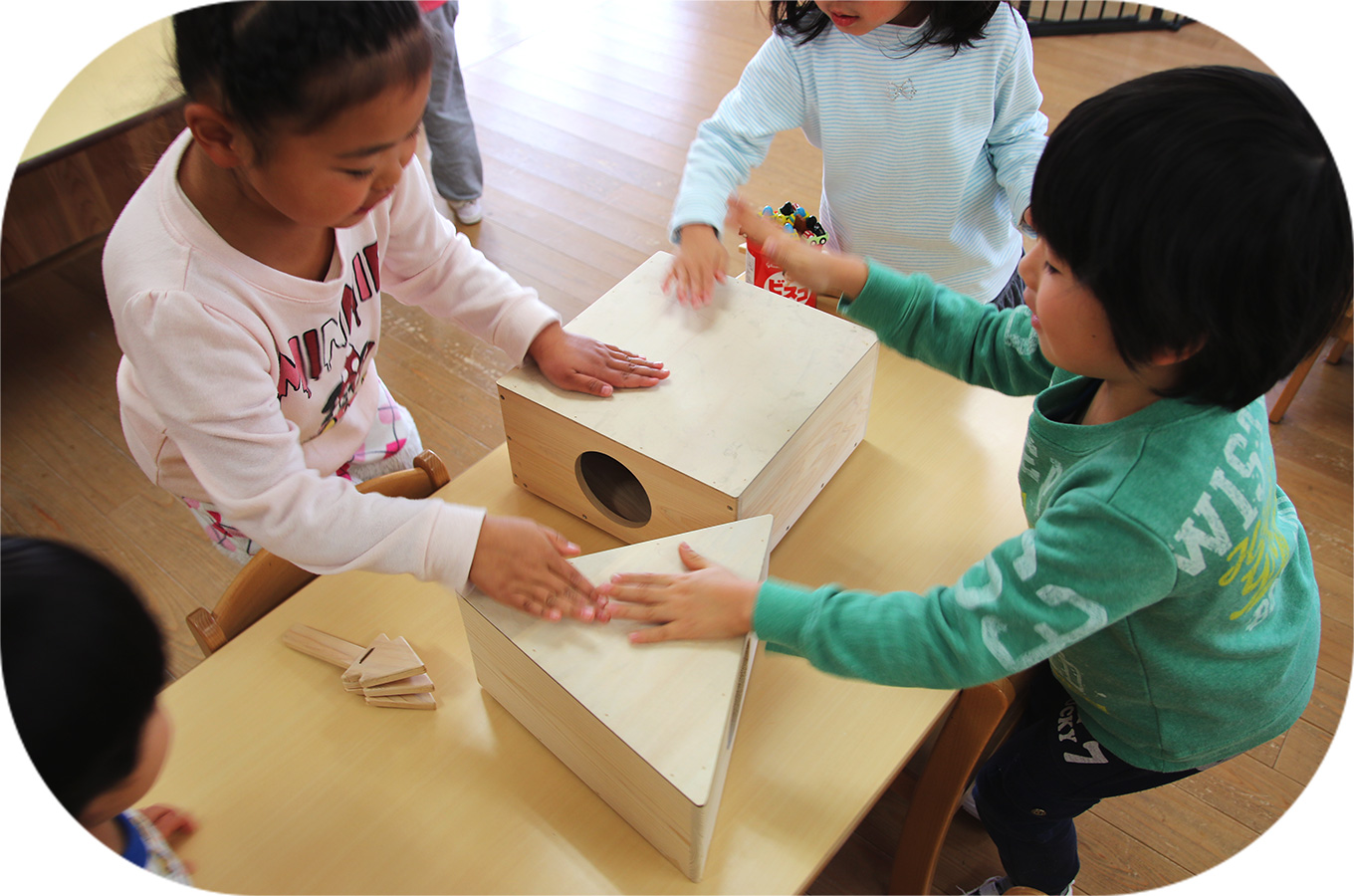 3人の子供達が、無垢の木で作られたおもちゃで遊んでいます