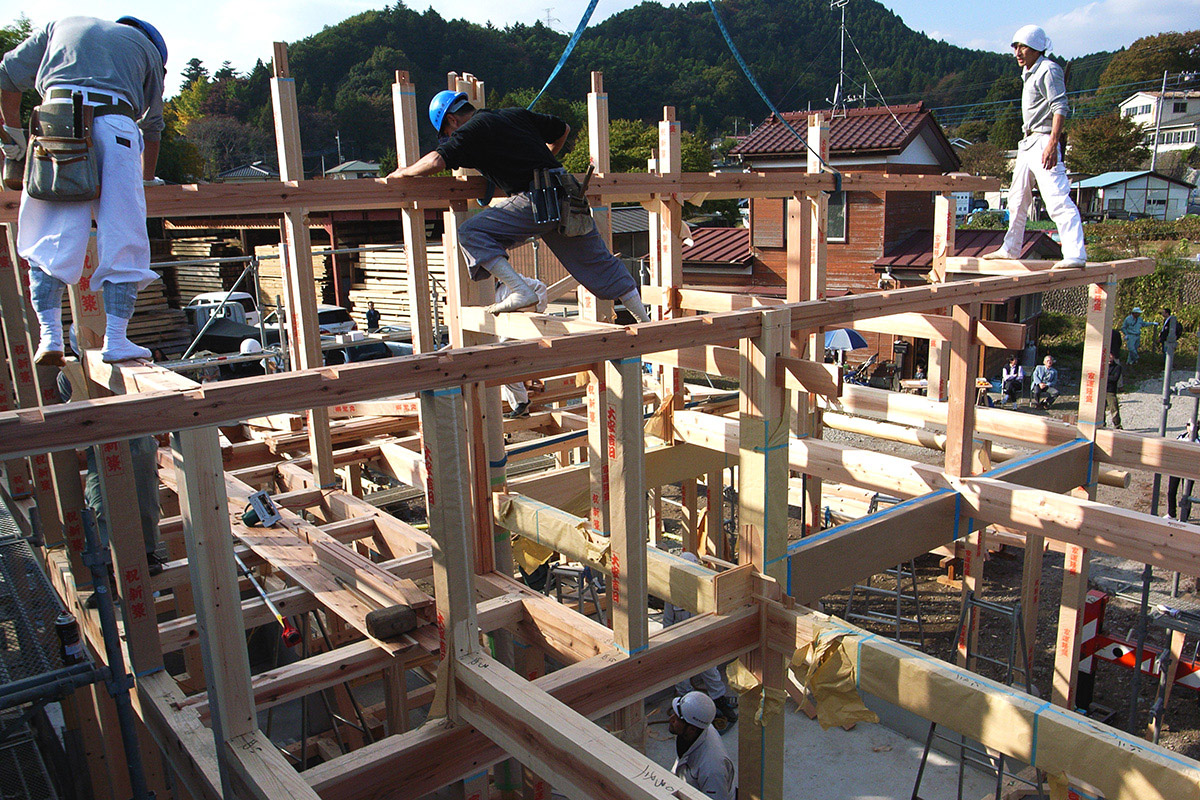 無垢の木材をたてよこに組んで、大工さんが家をつくる作業風景